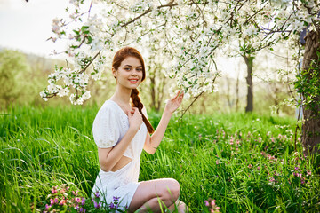 Naklejka na ściany i meble Young beautiful woman in a white dress posing in garden