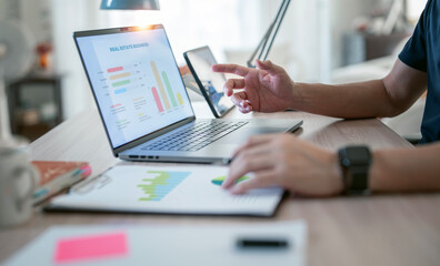 Young man using laptop computer at home, analyzing business graph chart planning for financial investment.