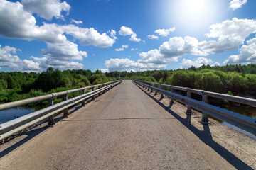 Asphalt road among the summer field under blue cloudy sky. Beautiful countryside landscape