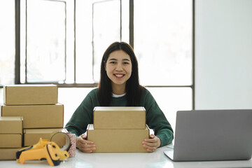 Female online business owner holding parcel and looking at camer