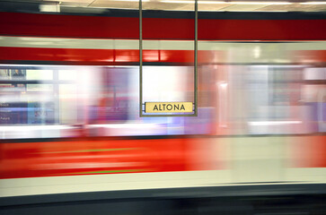 Altona station sign and passing by train behind it.