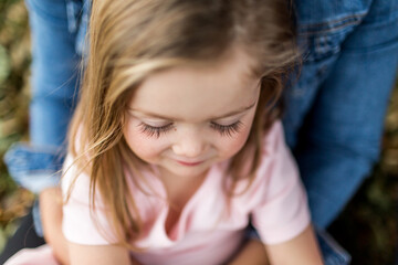 Close up of young girl sitting on parents lap