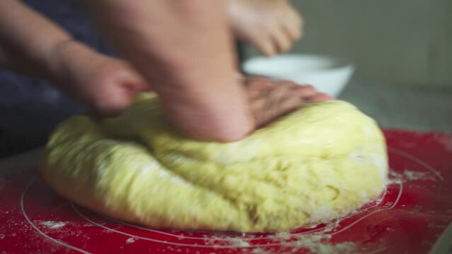 A woman kneads raw dough with raisins in the kitchen for making homemade pastries. close-up