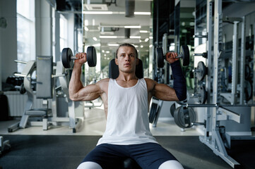 Strong healthy bodybuilder doing fitness training with dumbbells on press bench