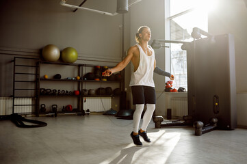 Young muscular man doing active training with jumping rope gym equipment