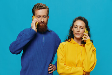 Woman and man cheerful couple with phones in their hands crooked smile cheerful, on blue...