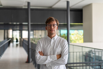 Smiling businessman with arms crossed on blurred office hall background