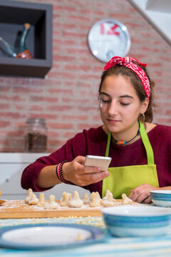 Teenage girl using the smartphone while working on traditional p