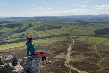 Hiker woman sitting on rock admiring wicklow mountain scenery