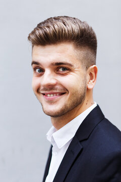 cheerful European man in a suit stands with an umbrella on the street