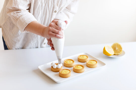 female confectioner is putting cream on lemon sweets in her kitchen