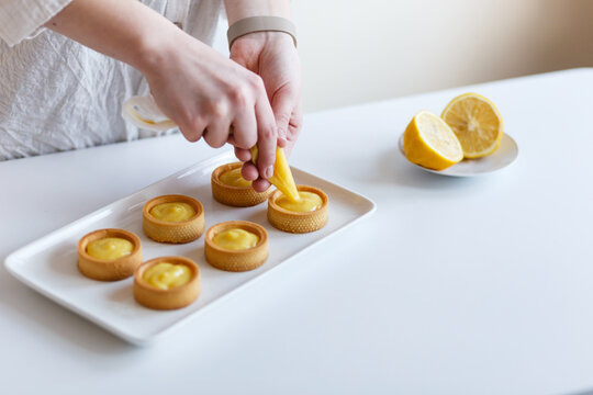 young female confectioner prepares lemon sweets in her kitchen