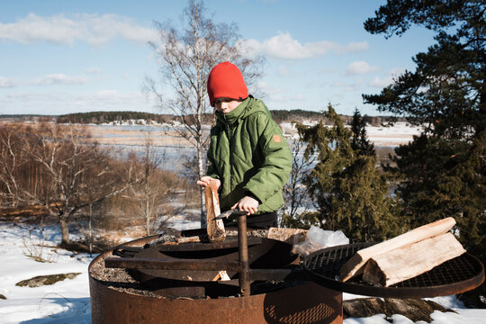 boy using a multitool pen knife taking bark off wood to make a fire