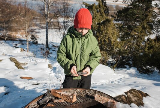 boy making a camp fire with a multitool in the snow