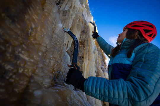A woman with long hair ice climbing