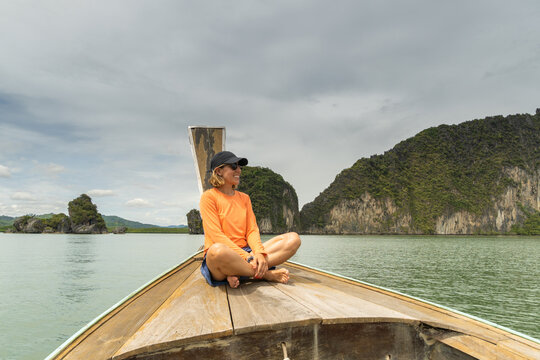 Woman smiling sitting in typical Thai boat admiring mountain landscape