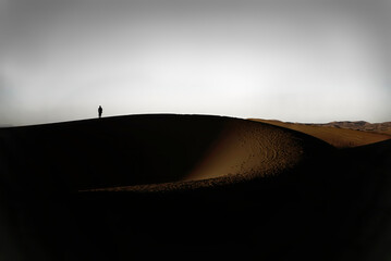 Arab man stands alone in the desert and watching the sunset.