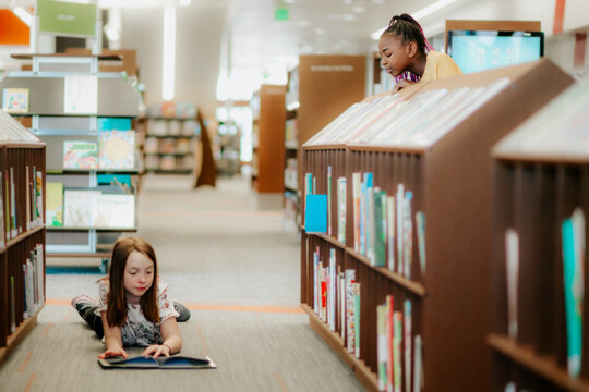 girl watching friend read in library
