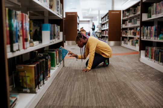 Young girl choosing book in library
