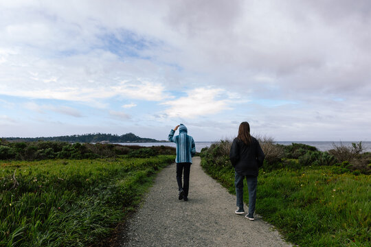 The Back Of Two Teenagers Walking Toward The Beach