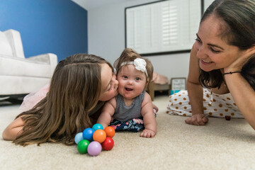 big sister playing with special needs sister on floor