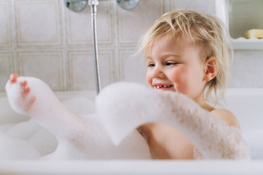Girl baby blonde bathes at home in the bathroom