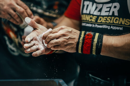 athlete powerlifter apply gym chalk on his hands for bench press. Singlet and wrist wraps Inzer