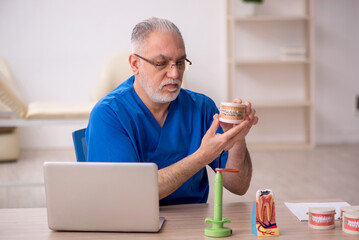 Old male dentist working in the clinic