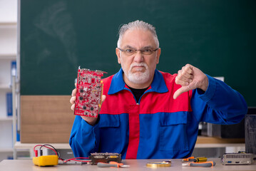 Old repairman repairing computers in the classroom