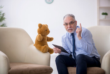 Old male psychologist and soft bear in the room