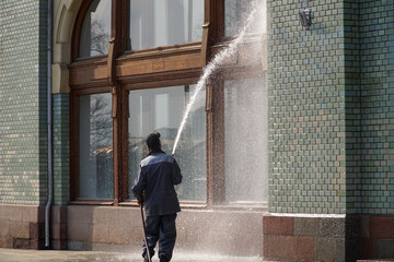 A uniformed worker washes a window at home with a powerful jet of water.