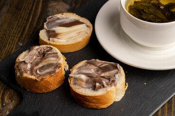 Green tea brewed in a mug and a baguette with chocolate butter