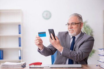 Old male employee holding credit card