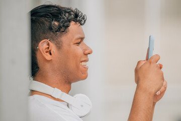 young latino male in the street looking at the mobile phone