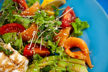 Healthy breakfast. Avocado and salmon toast, salad and vegetables. Microgreens on a plate. Food bowl. Lunch on a blue plate. Sauce and sesame seeds, lemon tomatoes. Top view.