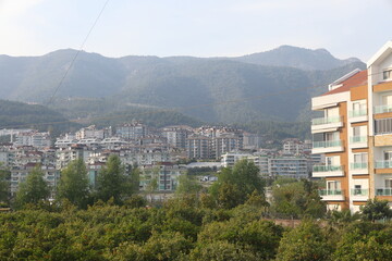 View of the highway, houses and mountains in Alanya, orange groves. Evening time, Türkiye, April 2023.