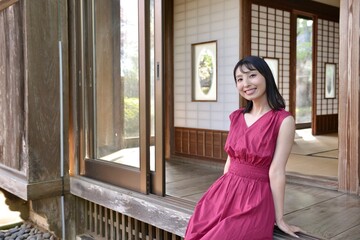 古民家の和室でくつろぐ赤いドレスを着た微笑む美しい女性	