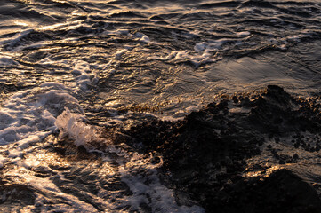 磯に打ち寄せる波と水面に反射する光