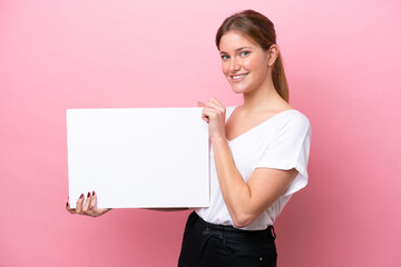 Young caucasian woman isolated on pink background holding an empty placard with happy expression