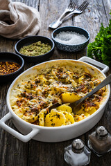 Potato casserole with mozzarella cheese and bechamel sauce on wooden table