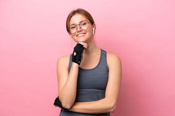 Young sport caucasian woman isolated on pink background with glasses and smiling