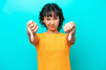 Young Argentinian woman isolated on blue background showing thumb down with two hands