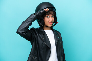 Young Argentinian woman with a motorcycle helmet isolated on blue background doing surprise gesture while looking to the side