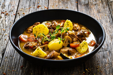 Delicious stew - cooked vegetables with roast meat on wooden table
