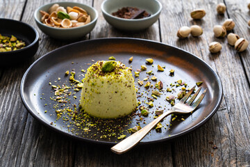 Panna cotta with pistachios on wooden table