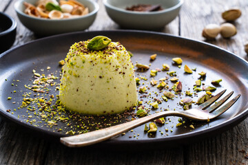 Panna cotta with pistachios on wooden table