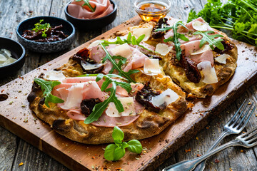 Pinsa Romana with mortadella, parmesan cheese and vegetables on wooden table
