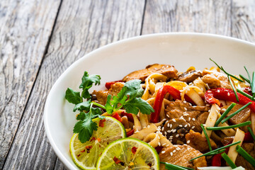 Asian food - chicken nuggets, noodles and stir fried vegetables on wooden table
