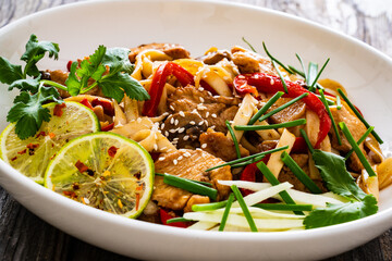 Asian food - chicken nuggets, noodles and stir fried vegetables on wooden table

