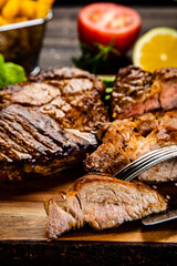 Barbecued meat, french fries, asparagus and vegetables on wooden board 
